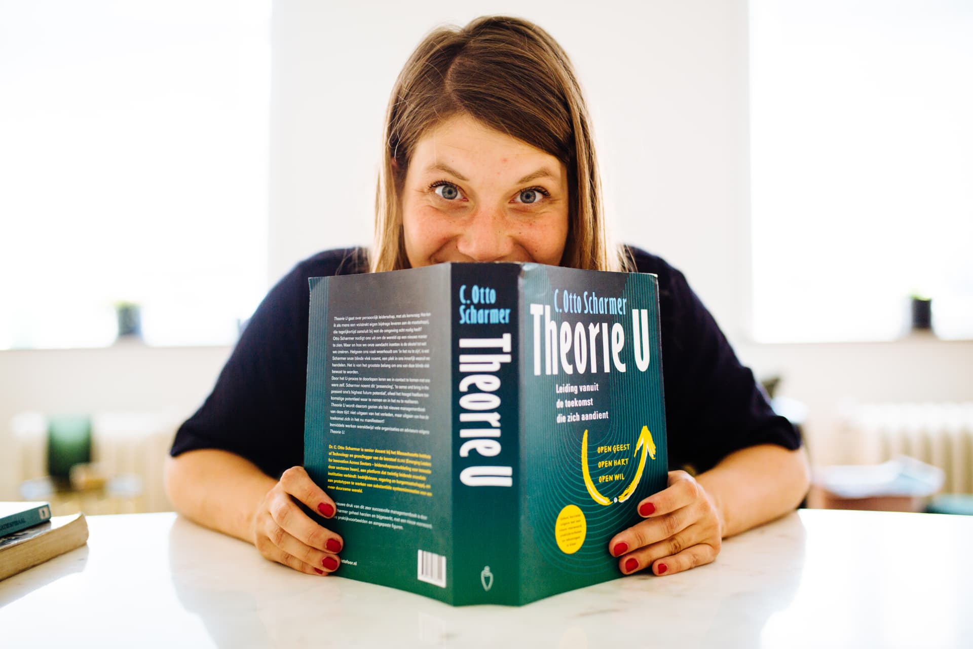Tessa kijkt speels over een boek heen